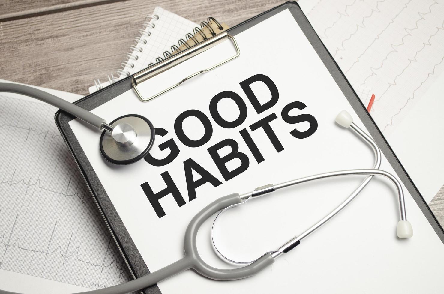 Good Habits text on notebook with pen, stethoscope and cardio charts on wooden background photo