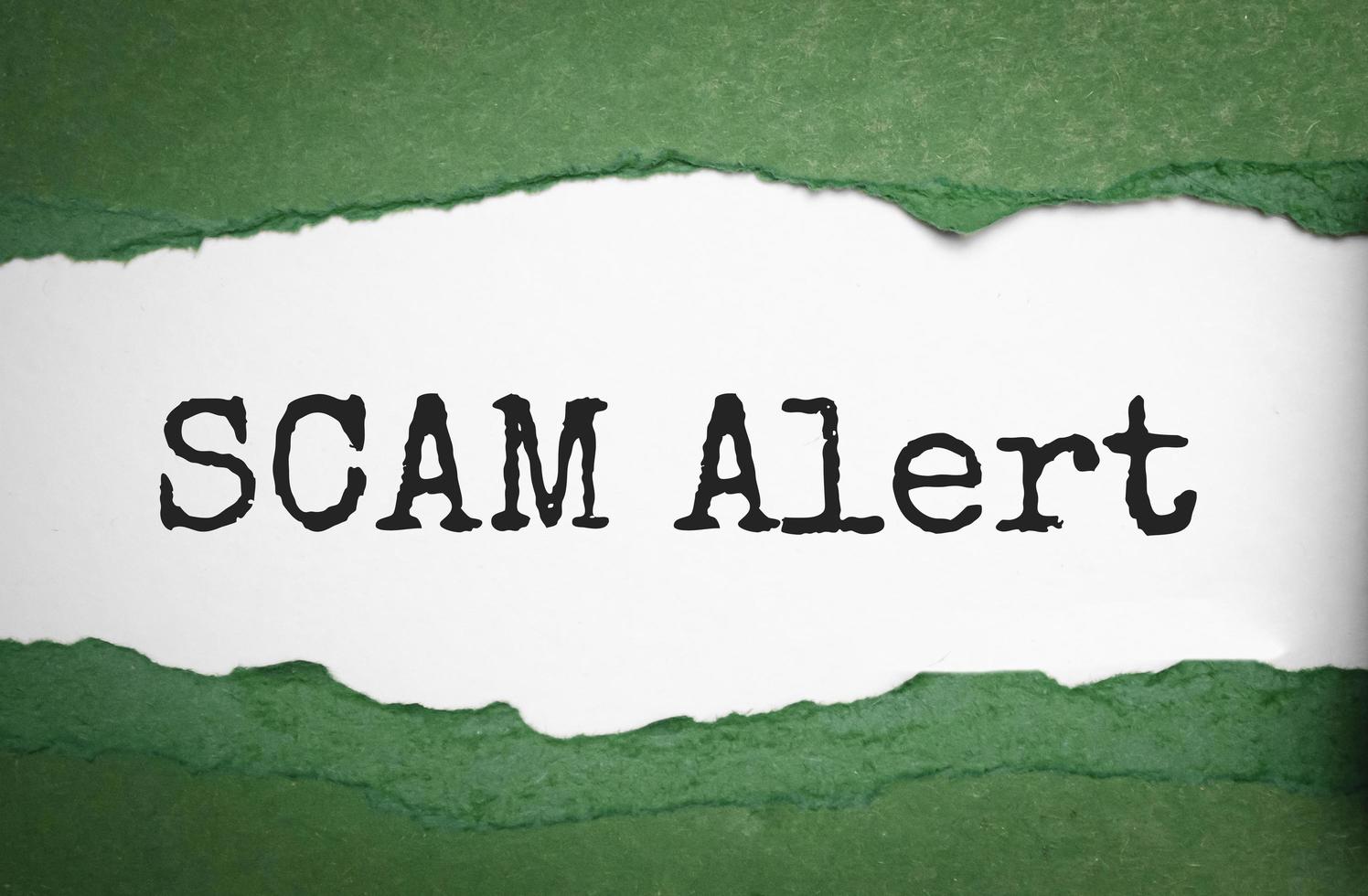 Green torn paper with a text of Scam on white cardboard photo