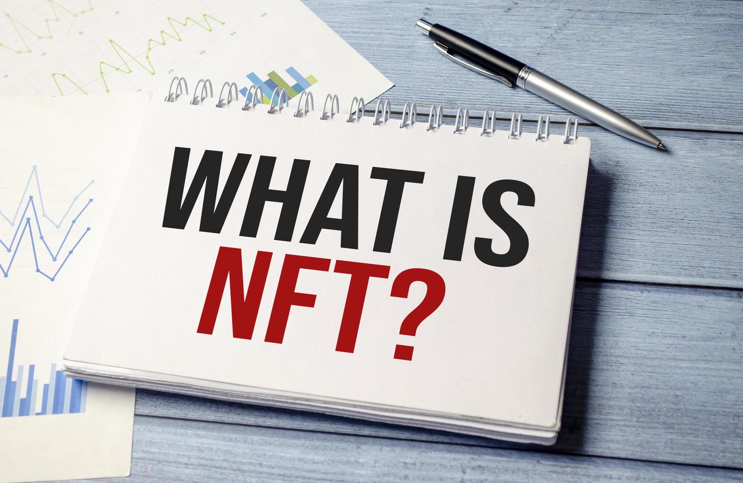 Paper with WHAT IS NFT on wooden desk photo