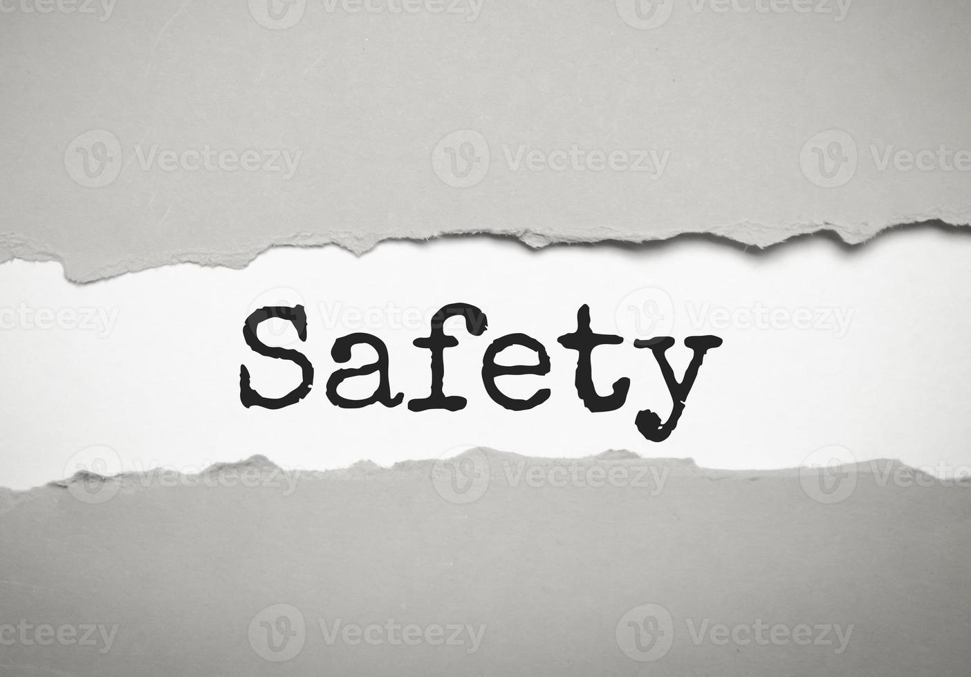 safety word under torn white paper on grey background photo