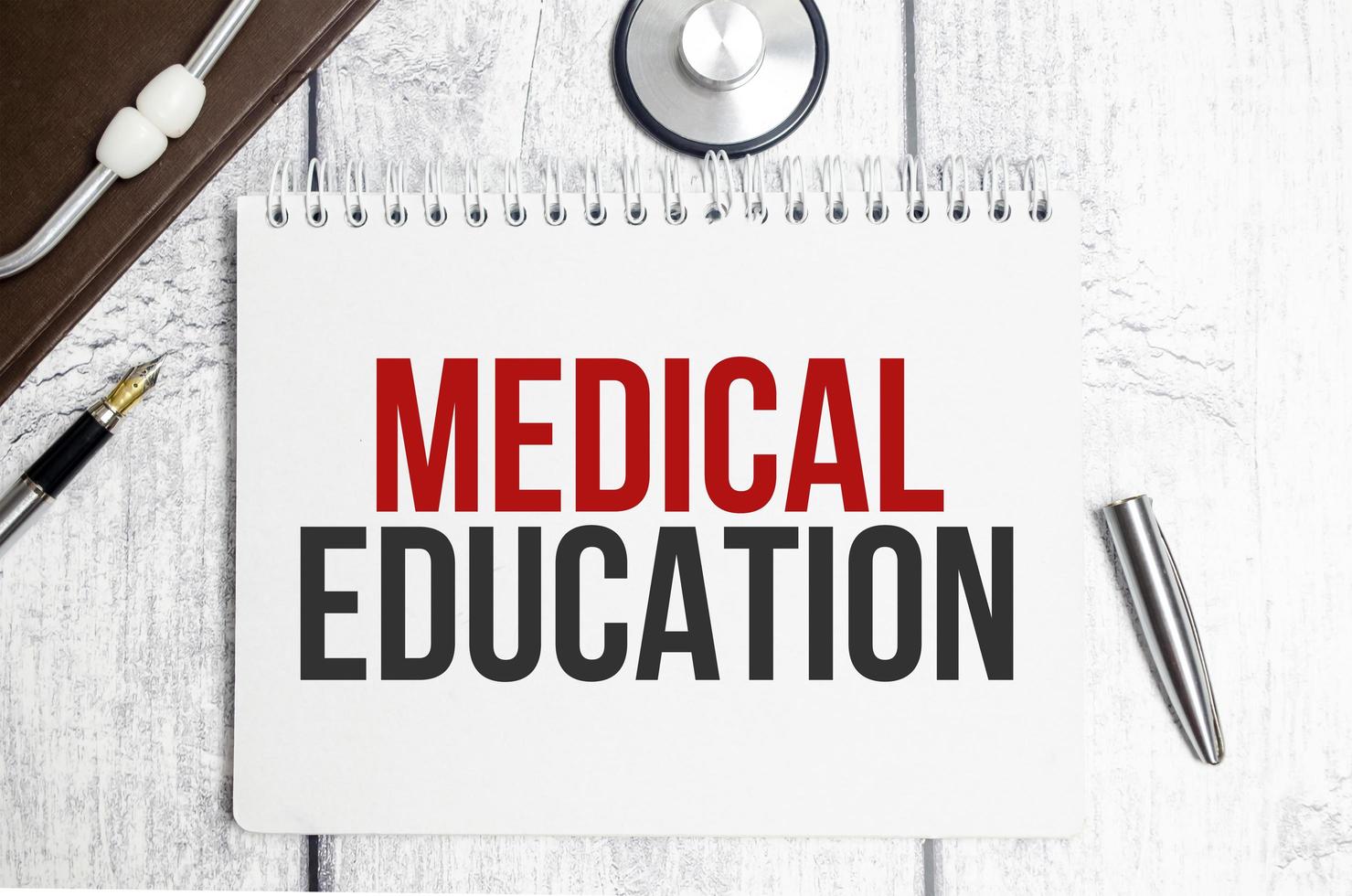 The text MEDICAL EDUCATION on a notebook on a white table next to a stethoscope photo