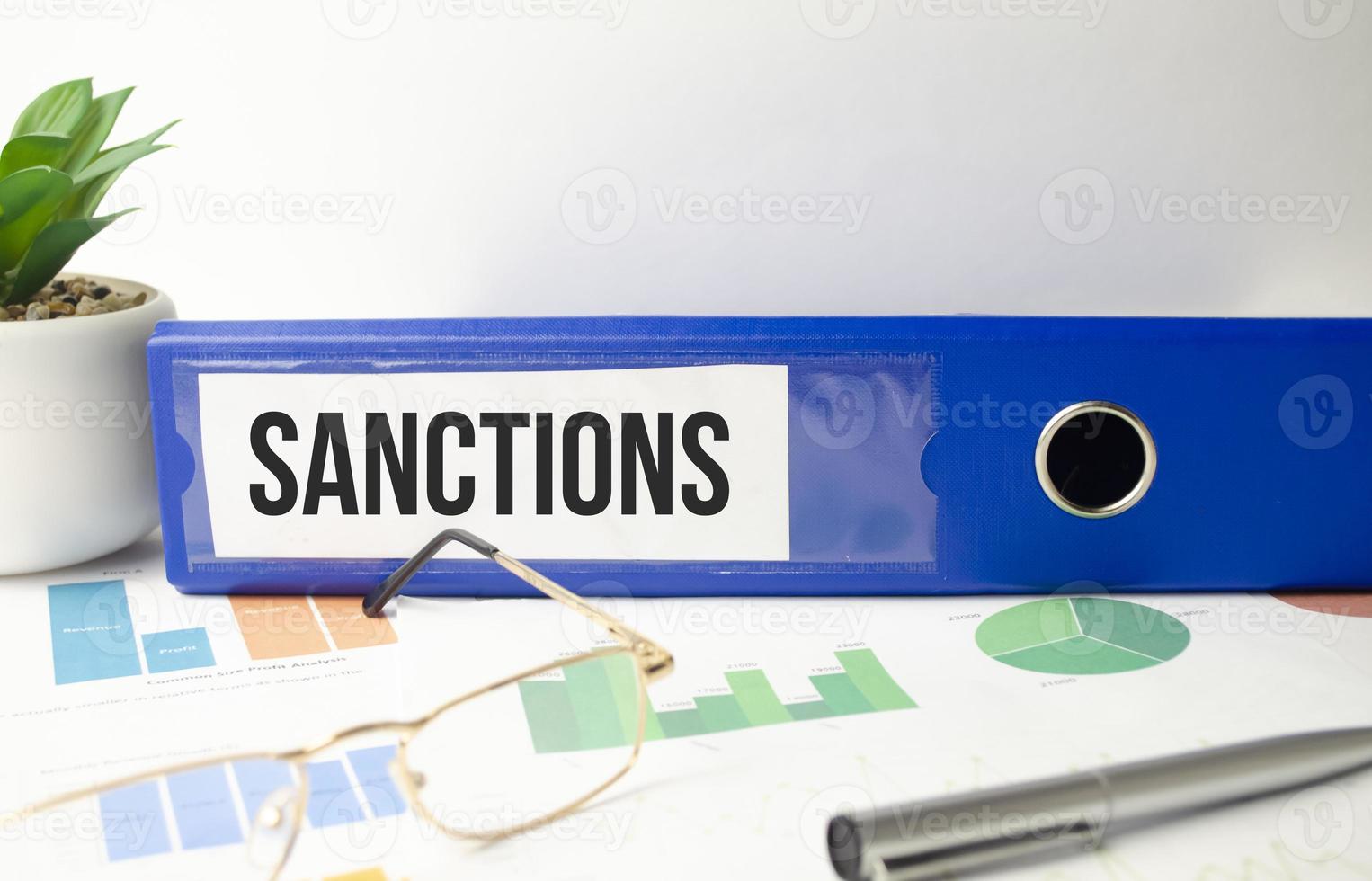 sanctions words on blue folder and charts. concept photo