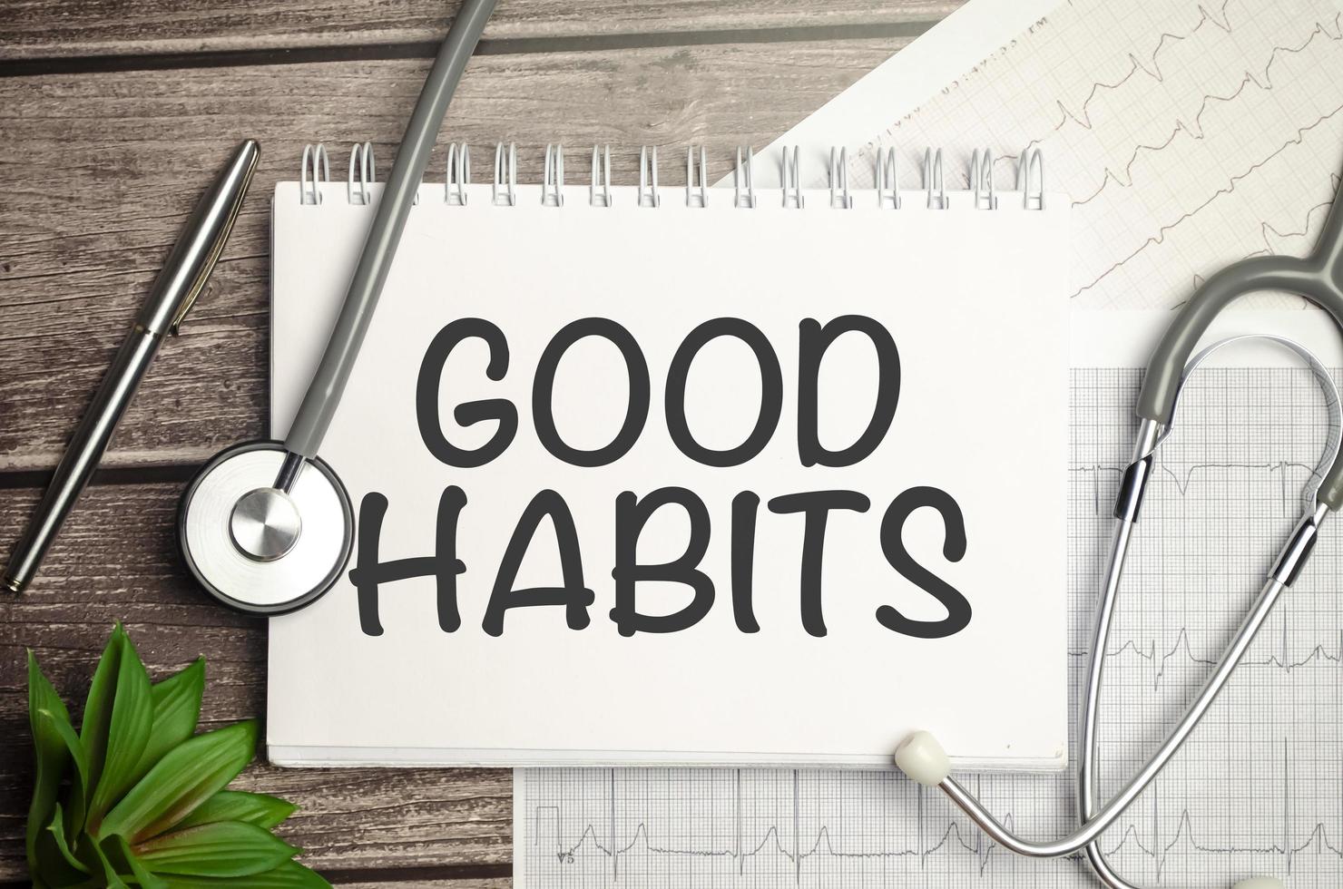 Good Habits text on notebook with pen, stethoscope and cardio charts on wooden background photo