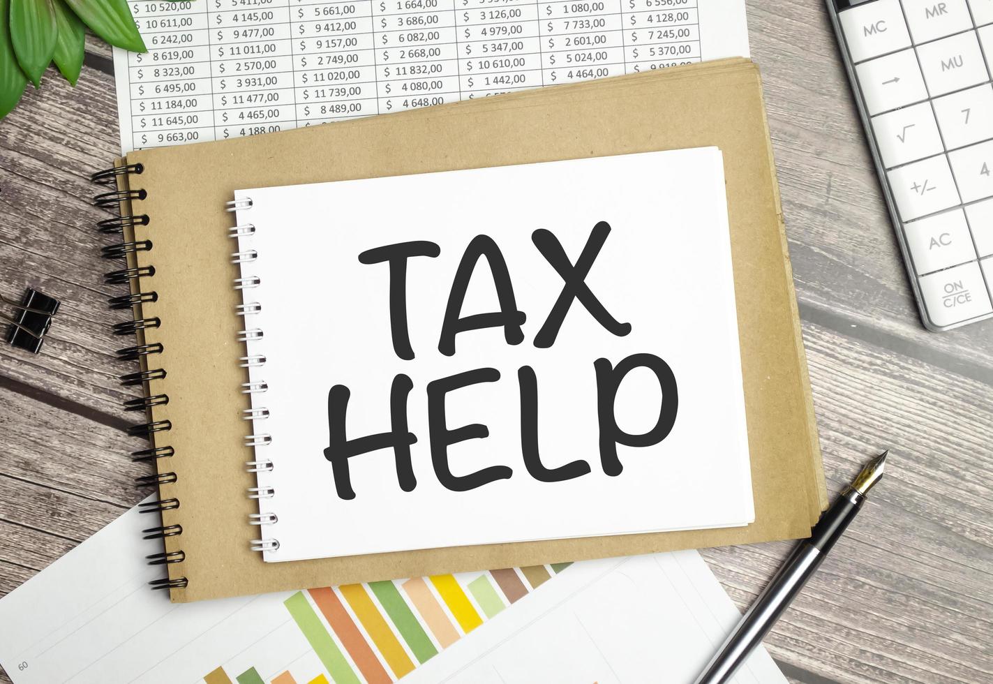 tax help word on notepad with pen, charts on wooden background photo