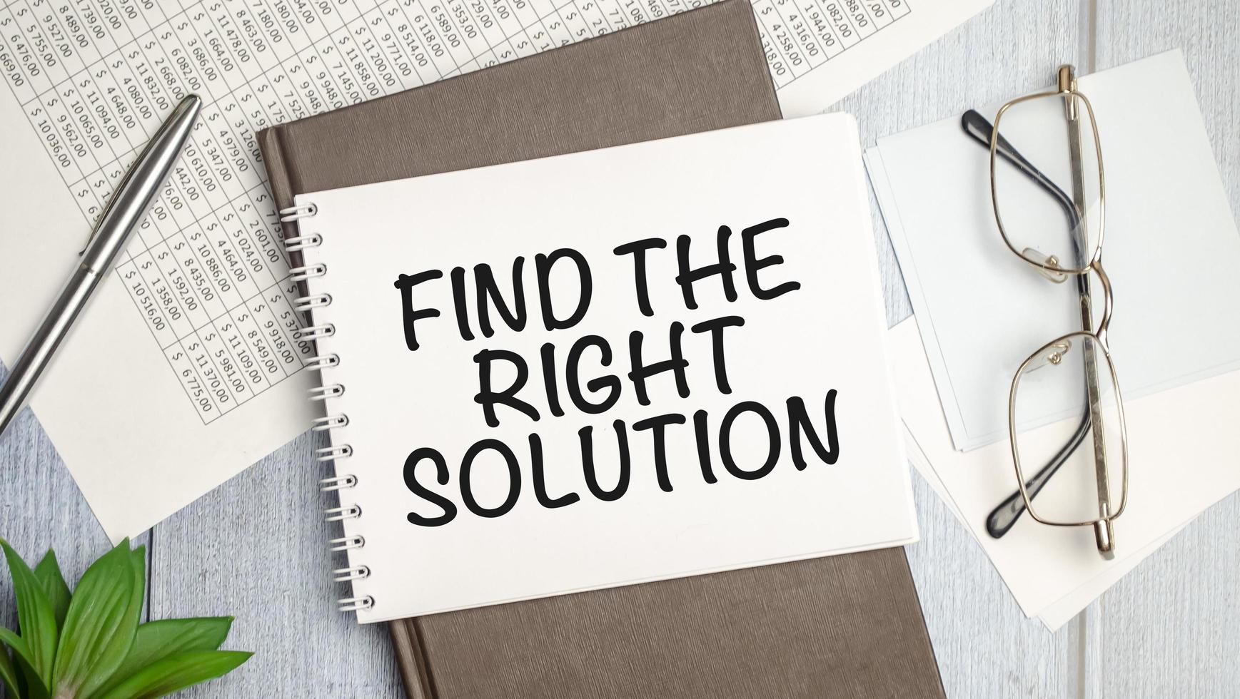 Find The Right Solution text on white notebook and pen on wooden background photo