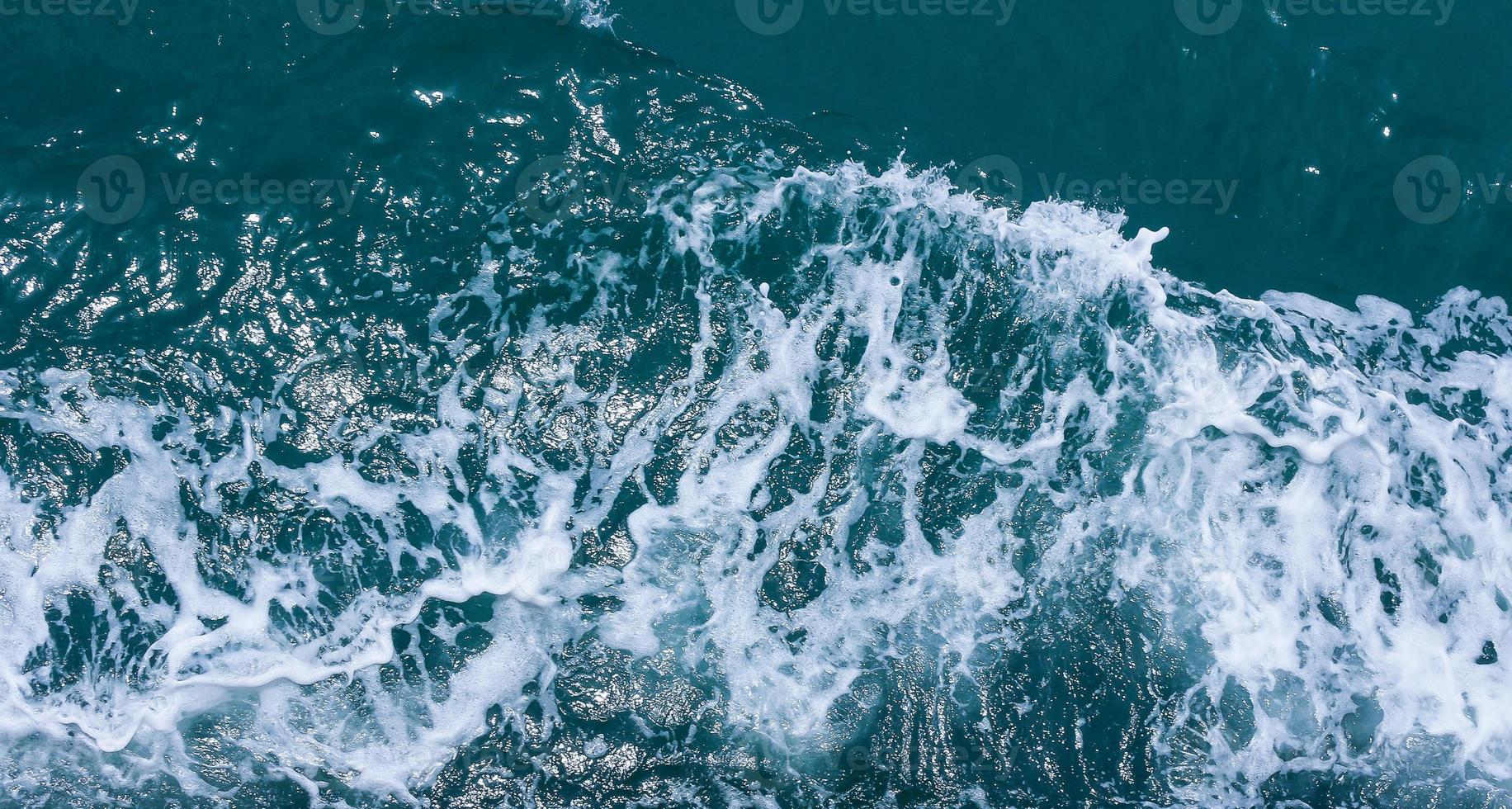 Beautiful sea waves with foam of blue and turquoise color. Abstract blue sea water with white wave. Blue and white waves of the ship road on the water sea ocean. photo