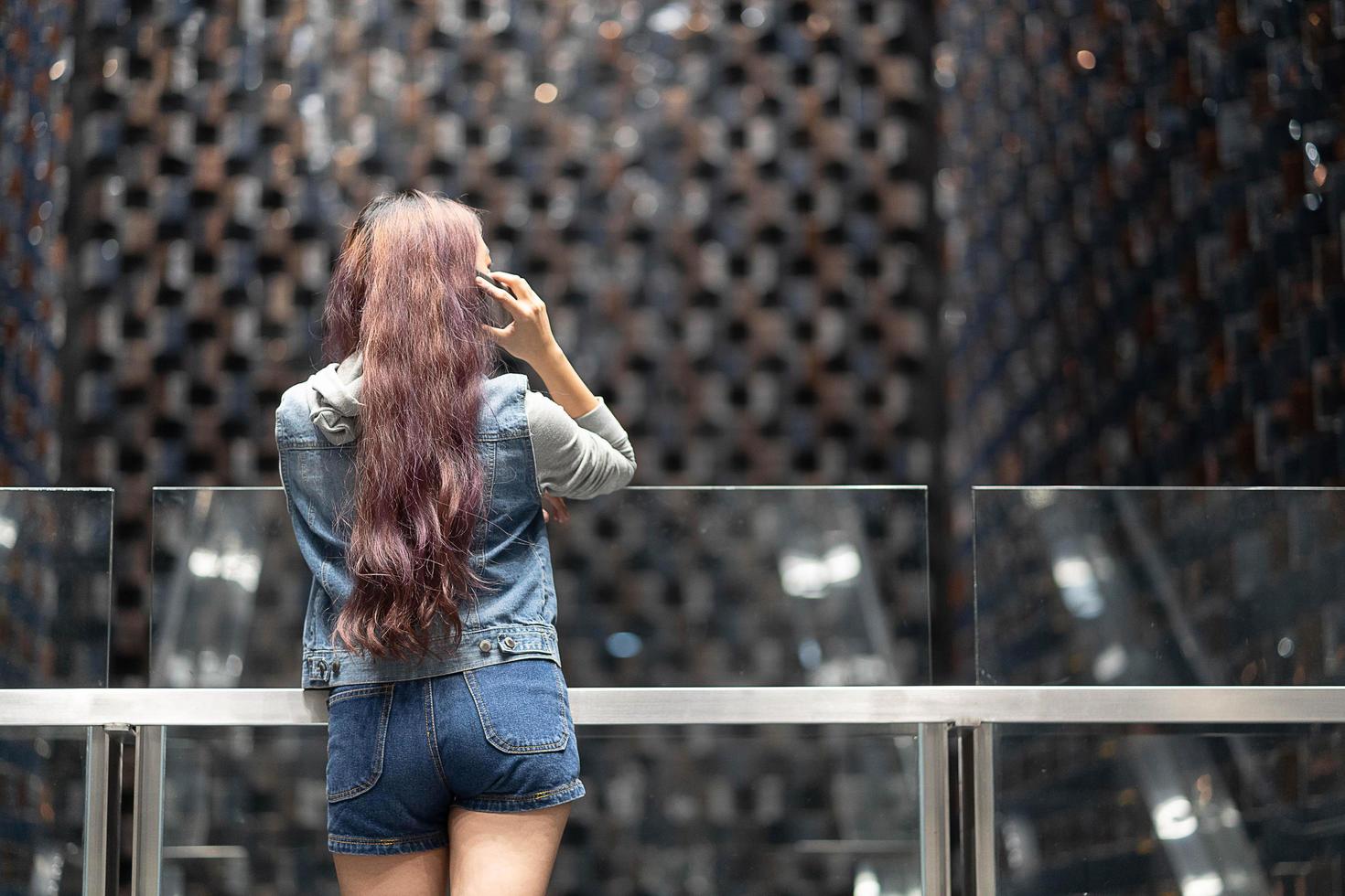 Caucasian brunette girl using a smartphone. talking with smart phone in the mall concept. Back view. photo