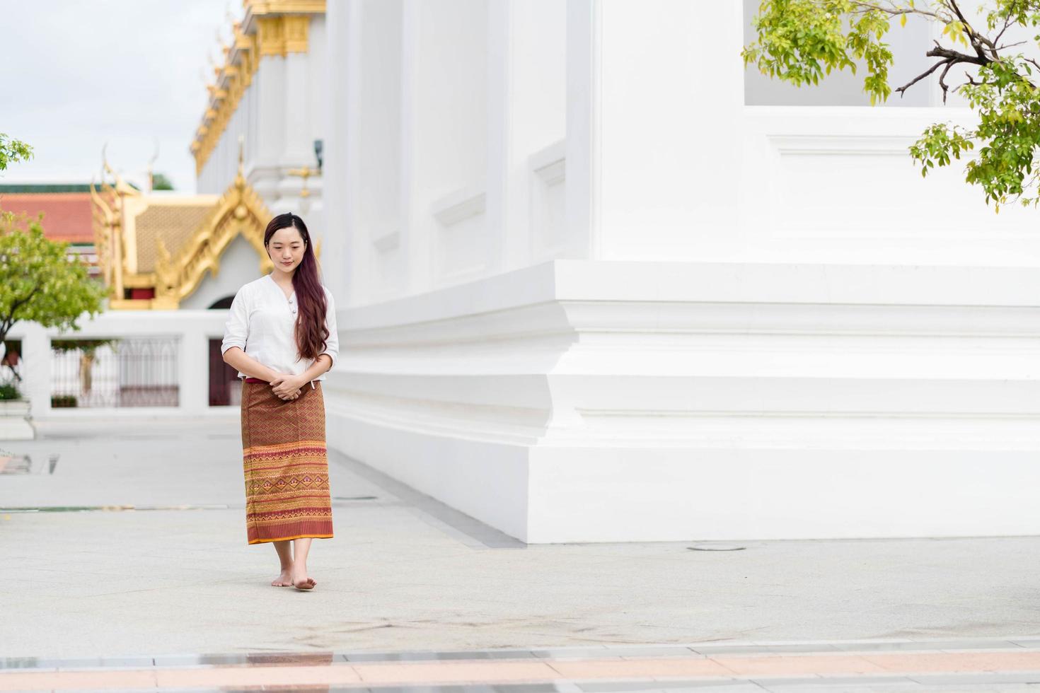 Asia woman wearing traditional dress of Thailand walking in chapel, Sanctuary Ratchanatdaram bangkok. photo