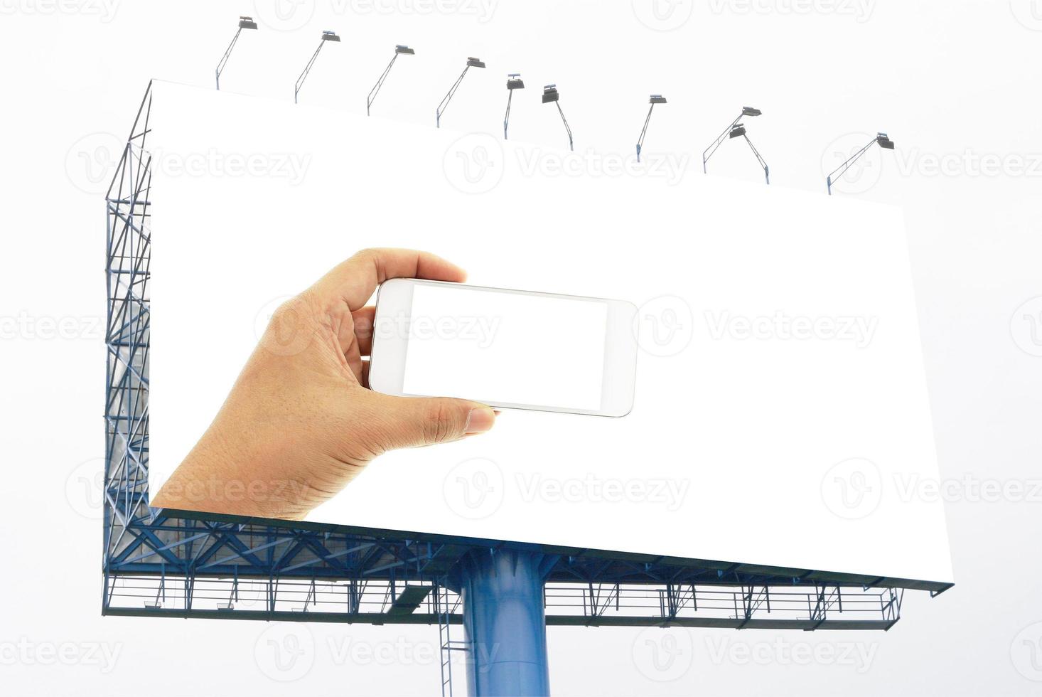 Hand holding white smartphone green screen on big billboard photo