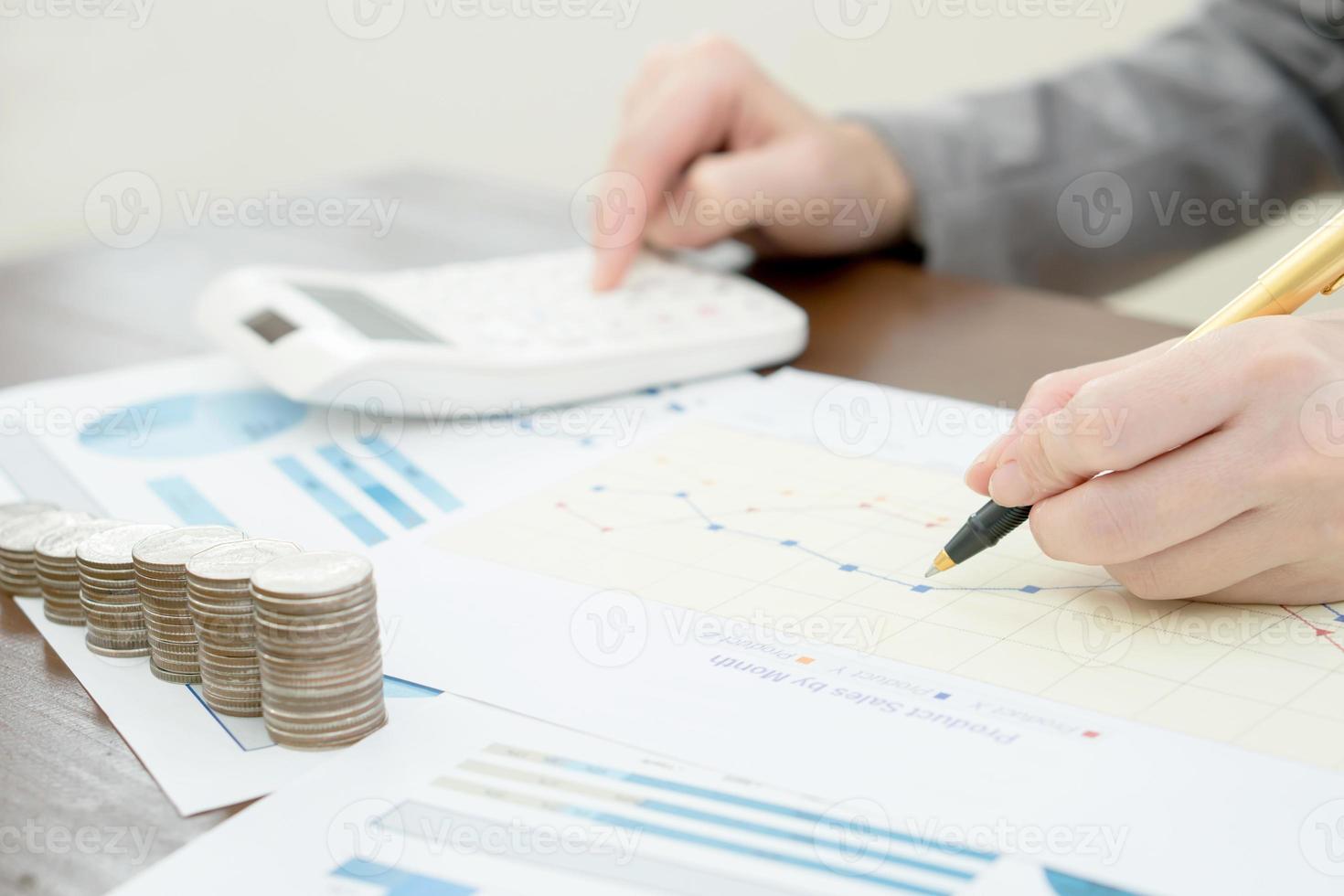 Close up woman using calculator on paper graph data photo