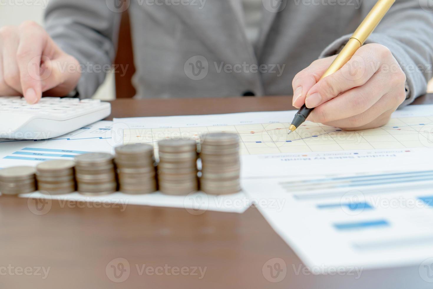 Close up woman using calculator on paper graph data photo