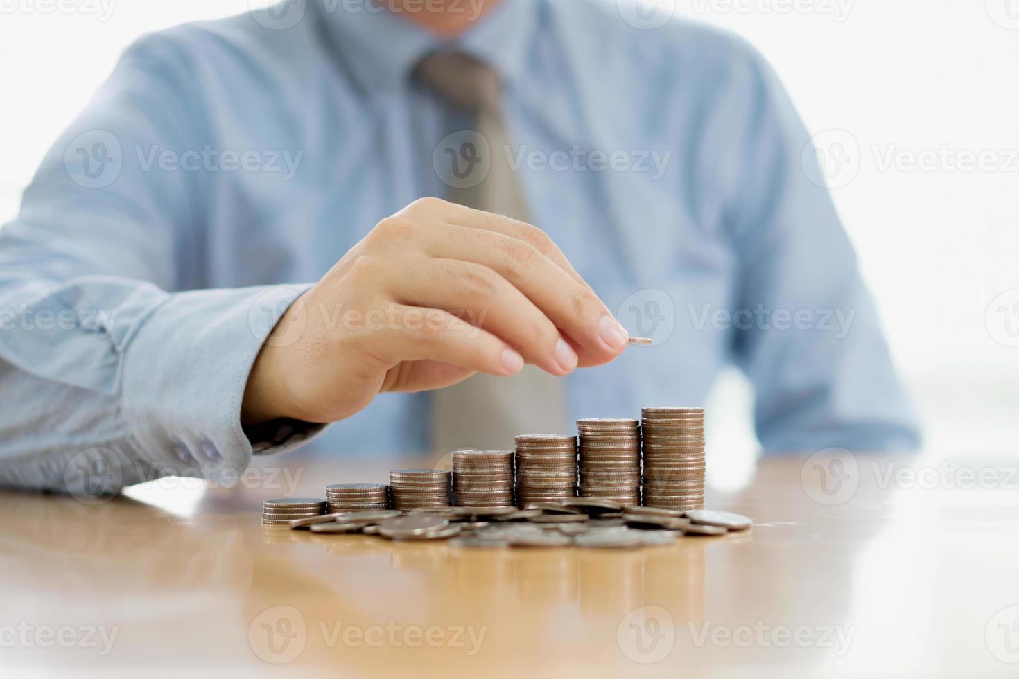 Businessman Sitting at Desk and Stacking Coins photo