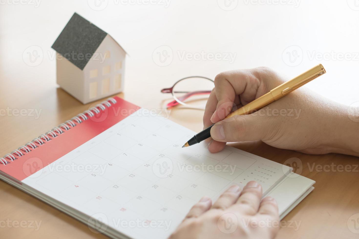 hand holding pen and marking on calendar photo