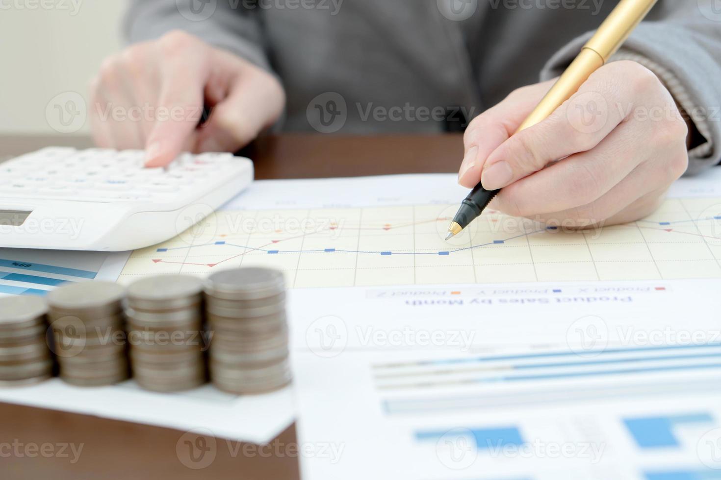 Close up woman using calculator on paper graph data photo
