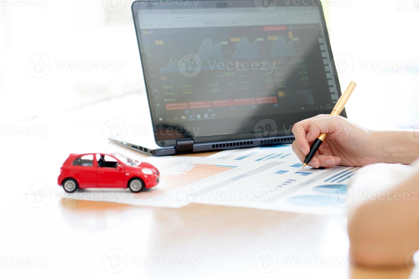 With Car Model And Stack Of Coins On Desk photo