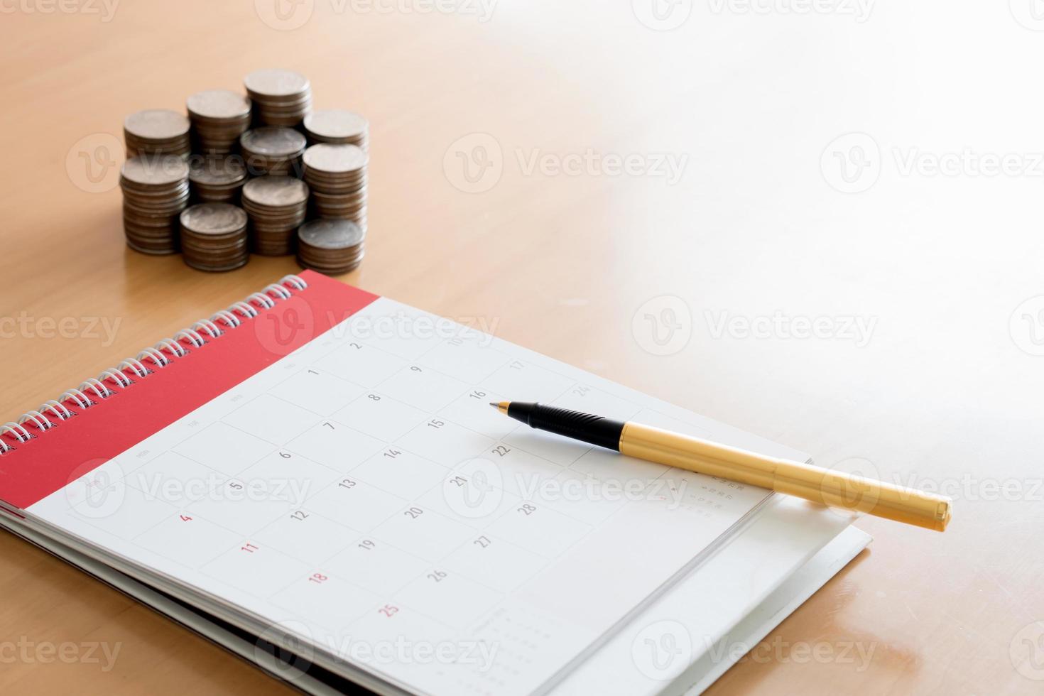 Pen and coins on calendar photo