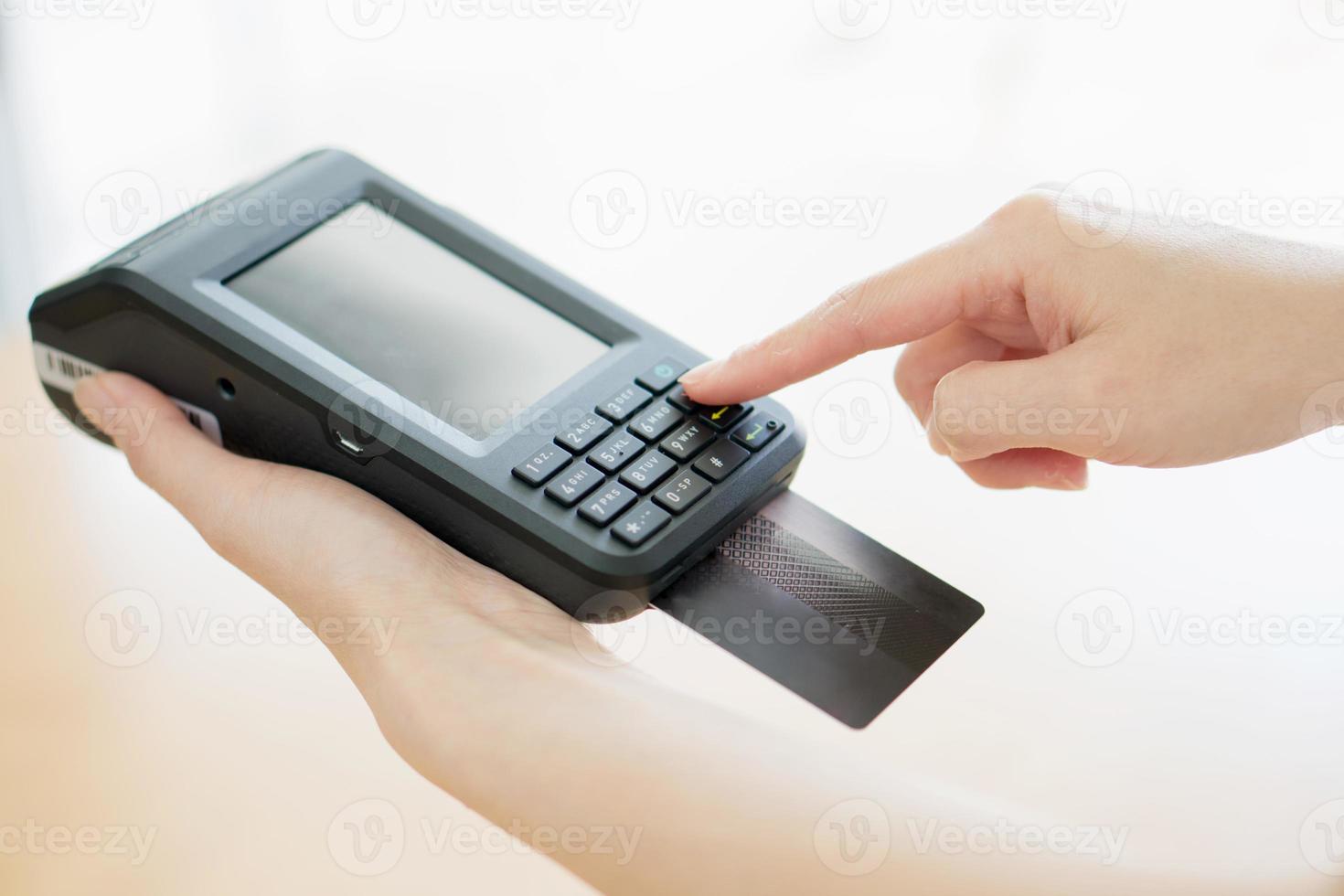 Hand with credit card swipe through terminal photo