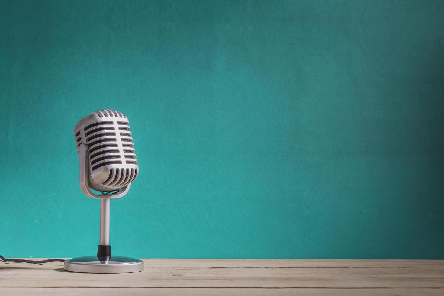 Retro microphone on wooden table with green wall background photo