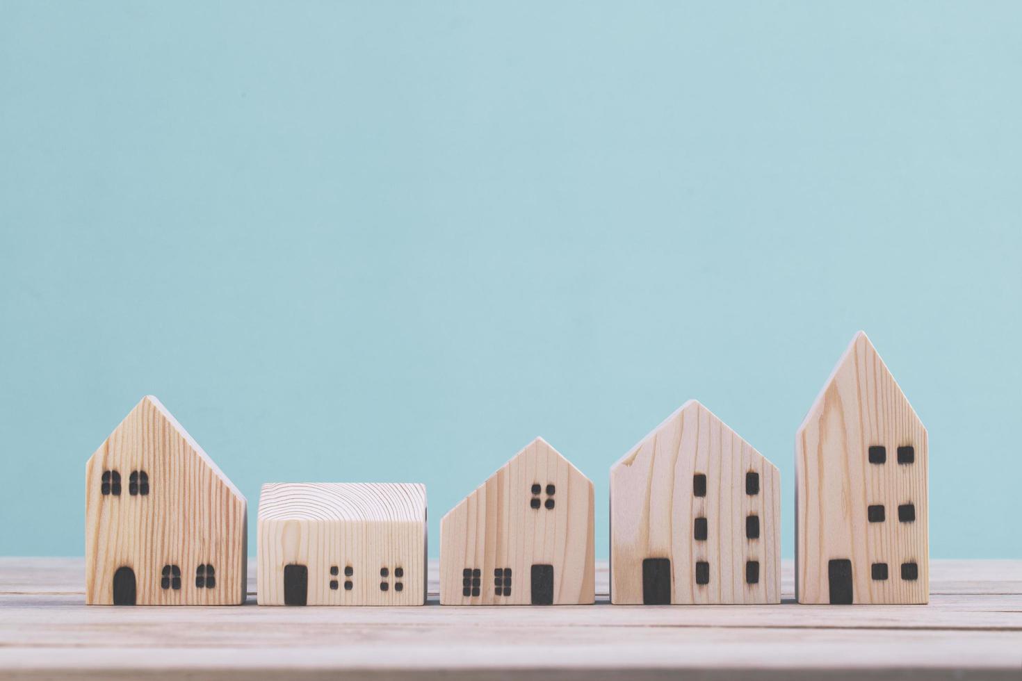 Building different wood house model on blue background , managing property investment concept photo