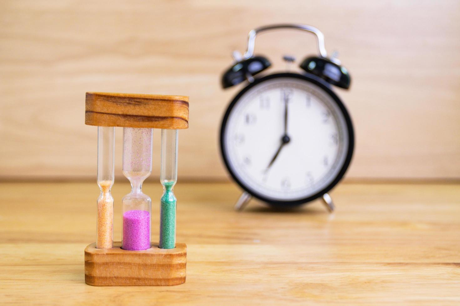 hourglass sand with the clock on a wood table selective focus hourglass photo