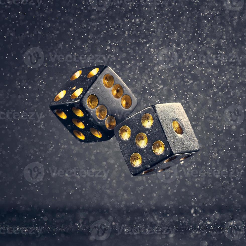 Two black dice are falling on a dark gray background. Photo with bokeh.