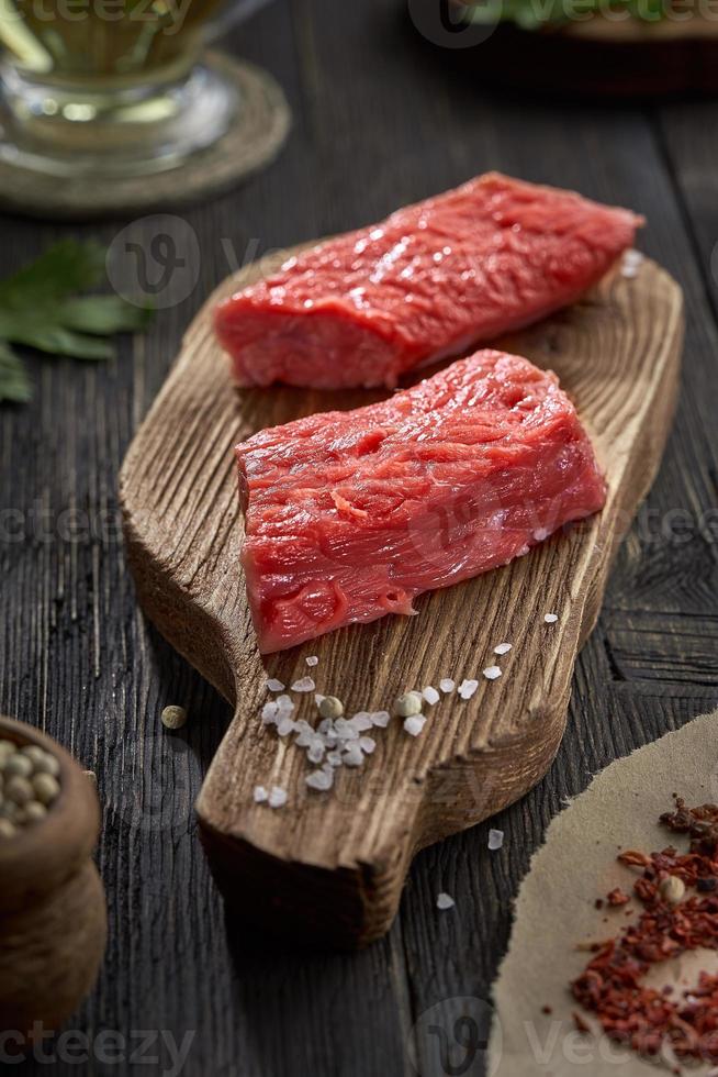 carne de res cruda fresca en rodajas y sal gruesa en una vieja tabla de cortar. foto