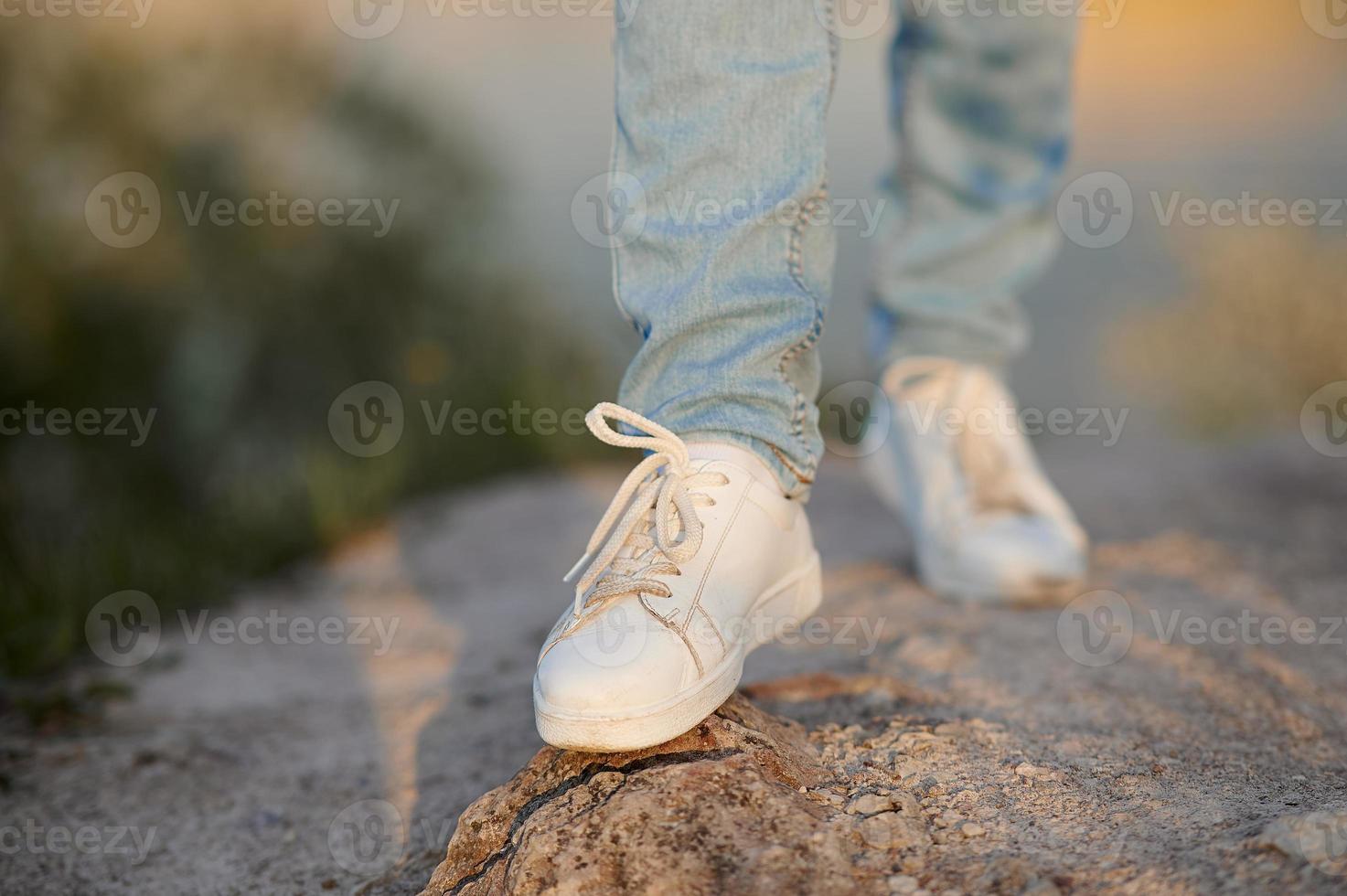Female legs in jeans and sneakers. One leg in a blur. photo