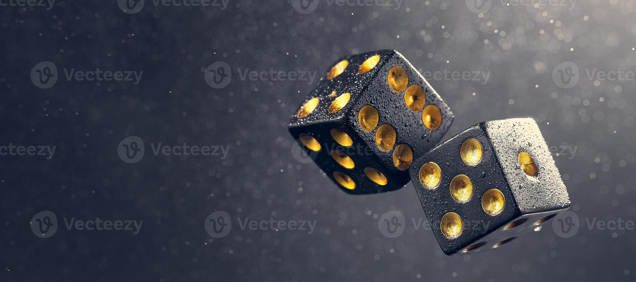 Two black dice are falling on a dark gray background. Photo with bokeh. Photo with copy space. The light falls from the side.