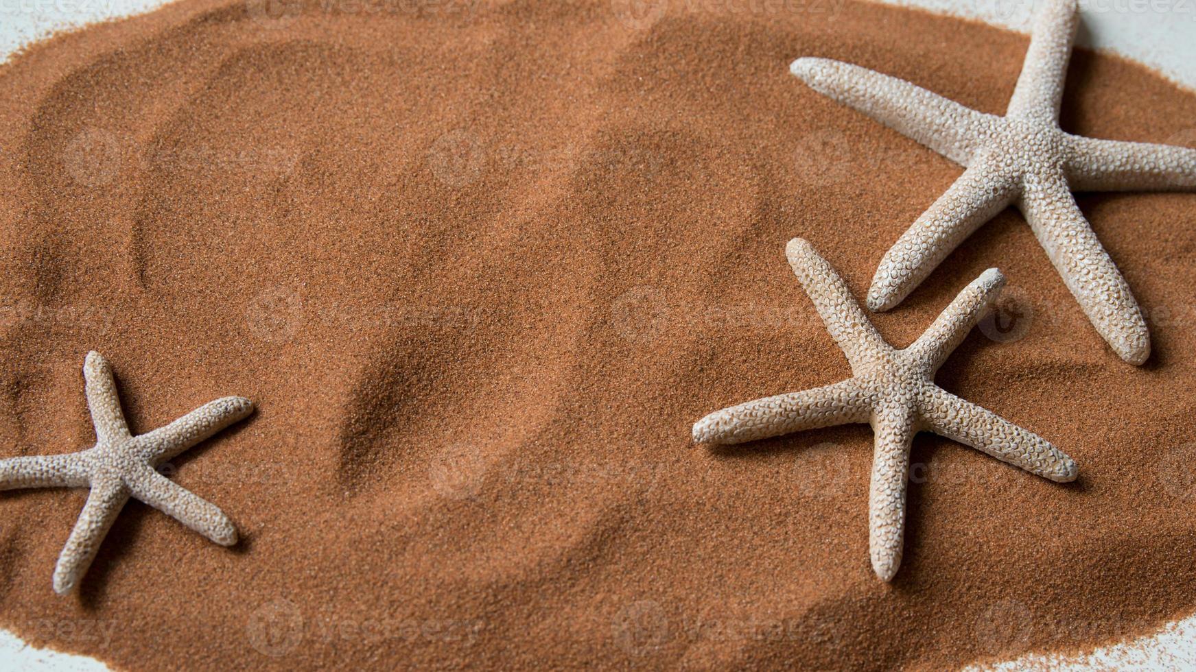 Holidays. Background with beach sand and three starfish. photo