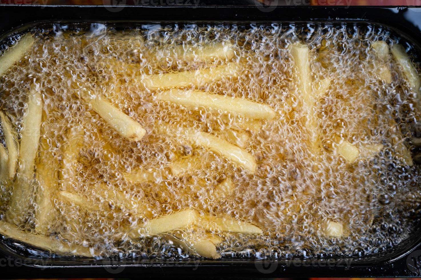 French Fries frying with boiling oil in electric fryer photo