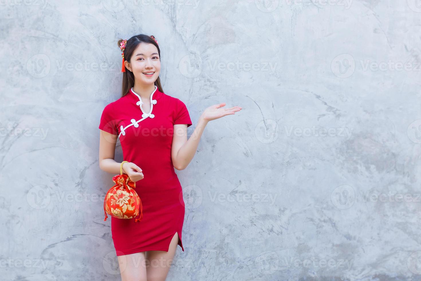 Asian beautiful girl in red dress stands holding a red bag among old city center Chinese new year theme. photo