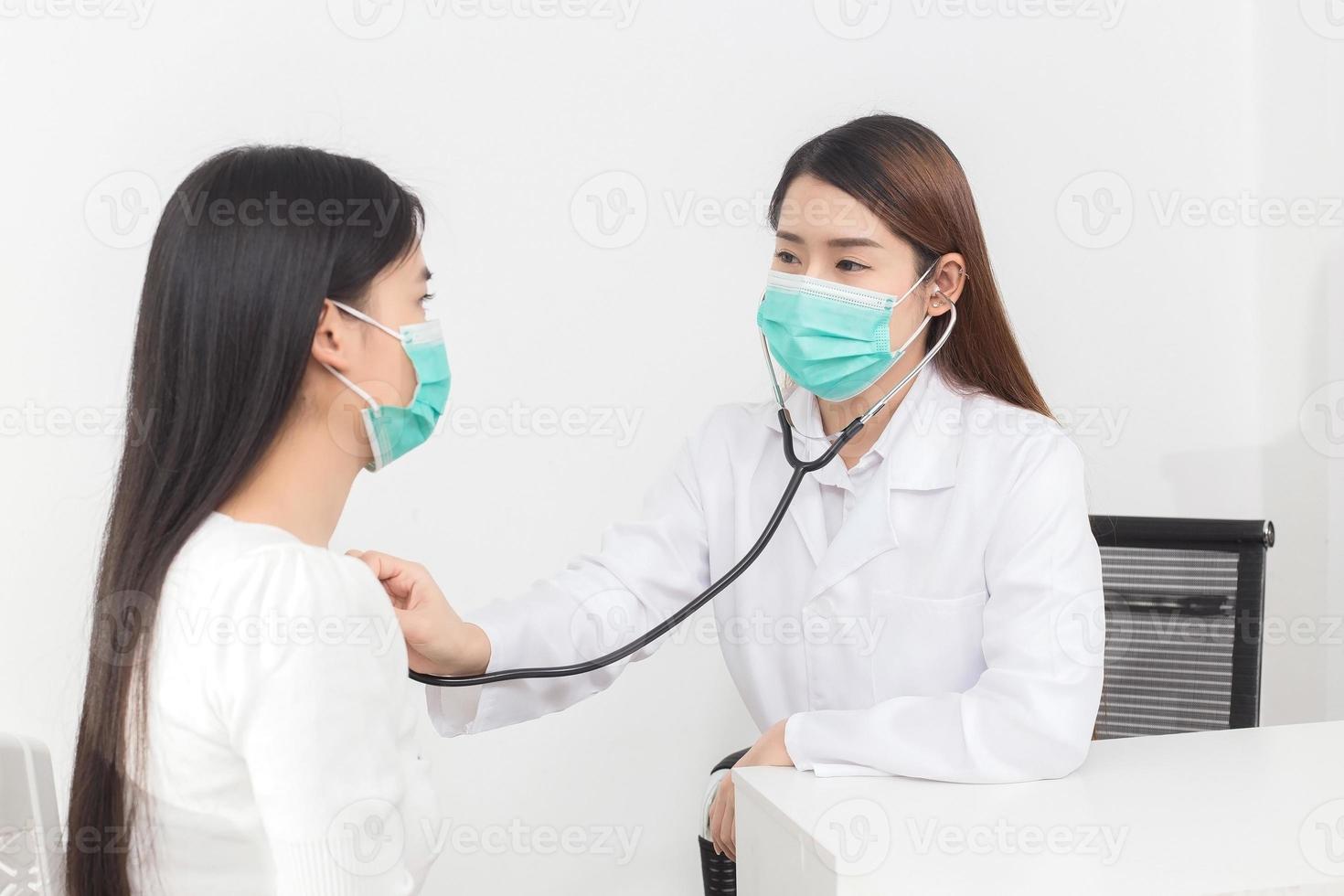 una doctora asiática examina los síntomas de su paciente mientras ambos usan mascarilla médica para prevenir la enfermedad de infección covid 19 en el hospital. foto