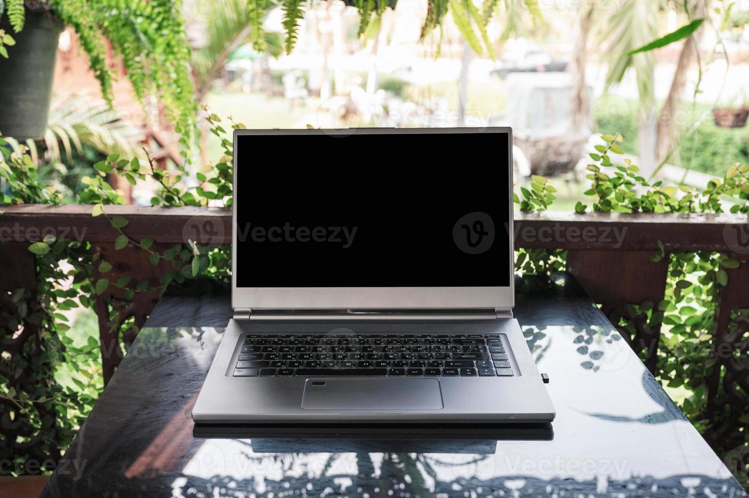 Open modern gray laptop on glass table in spring garden photo