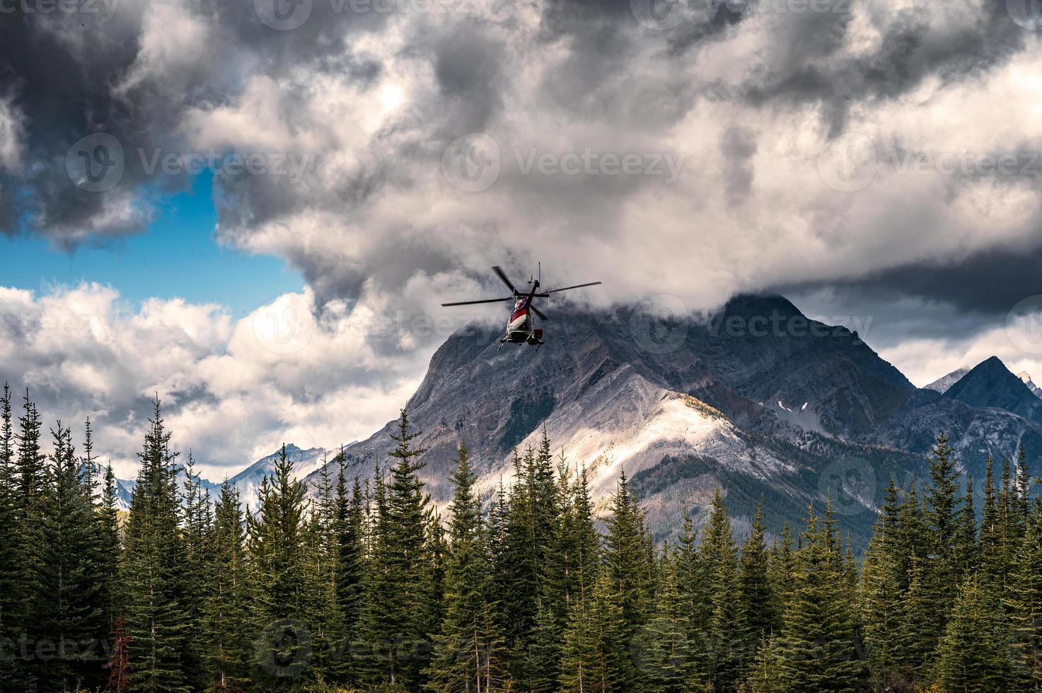 helicóptero comercial volando con cielo oscuro hacia el parque provincial de assiniboine foto