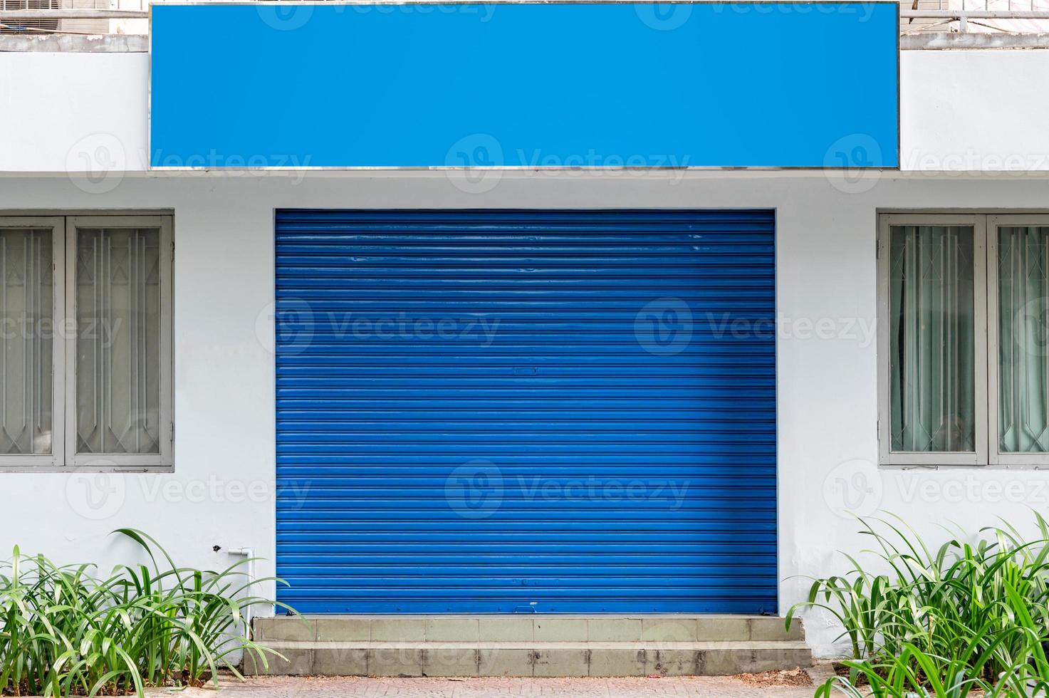 Closed blue shutter roller door with blank billboard photo