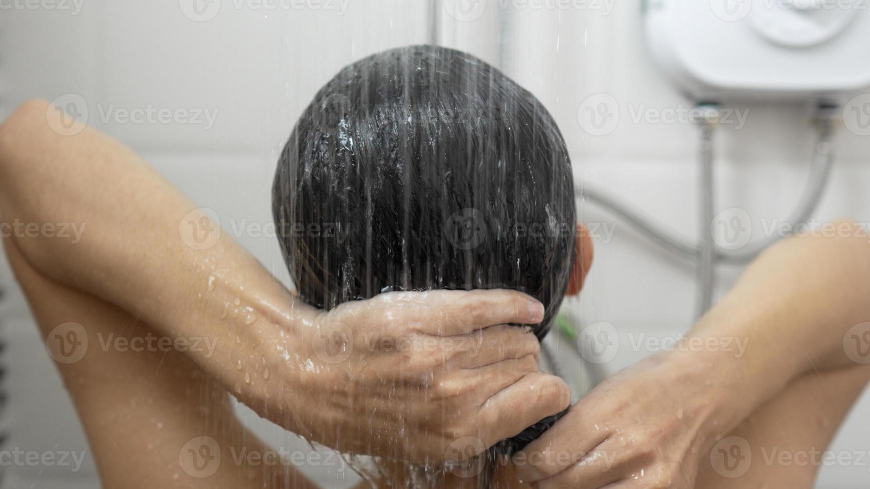 Young woman taking a shower and washing her hair in the bathroom photo