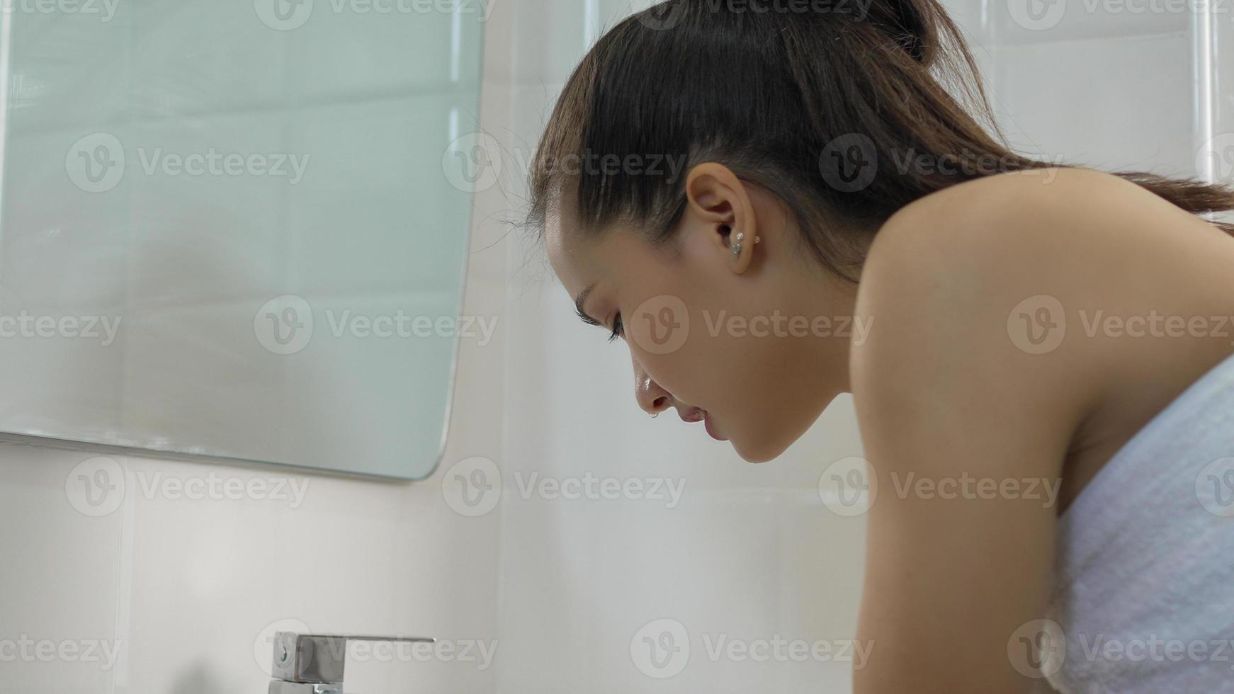 Young woman washing her face in the bathroom at home photo