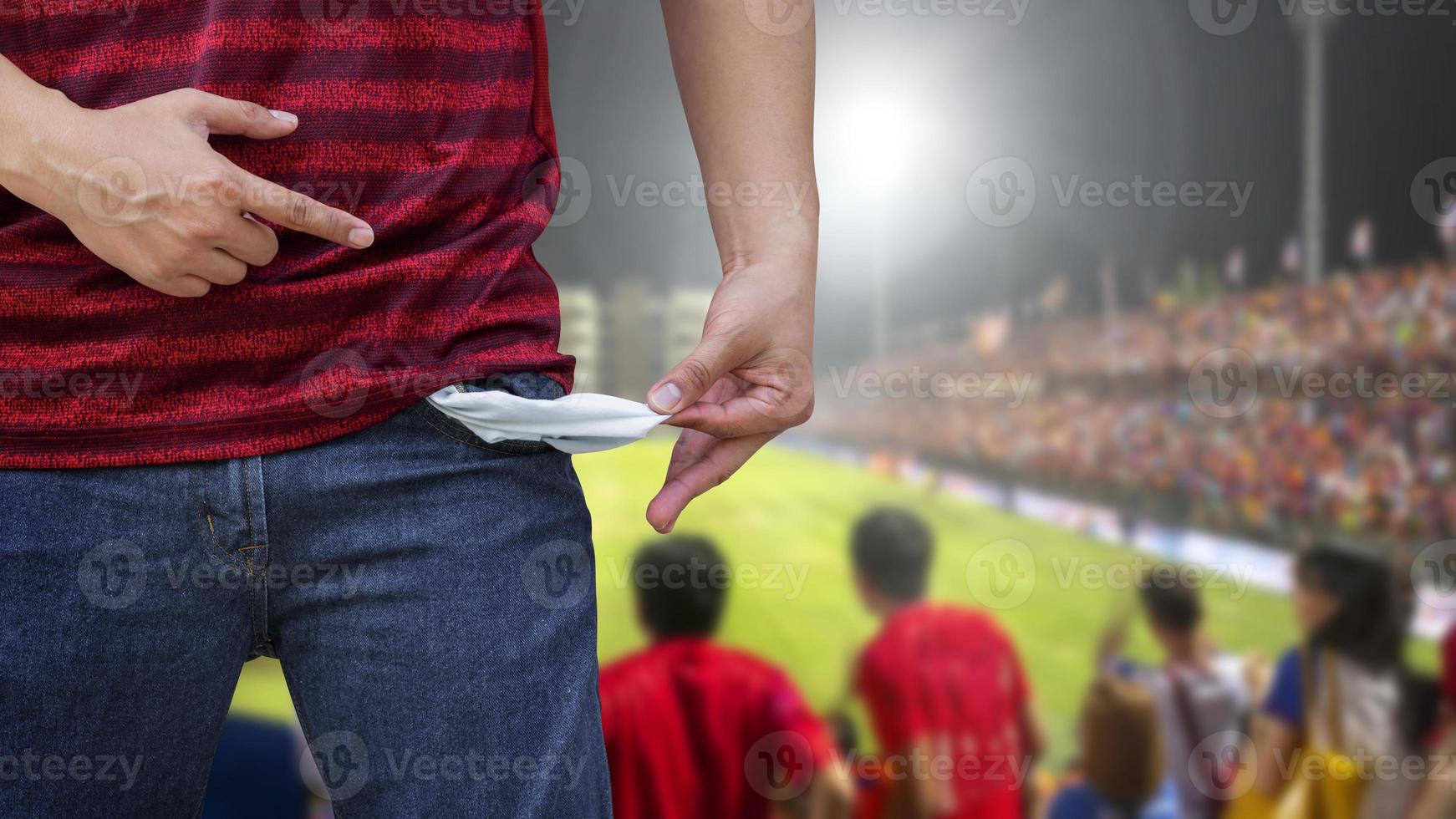 hombre mostrando sus bolsillos vacíos en un estadio de fútbol borroso. foto