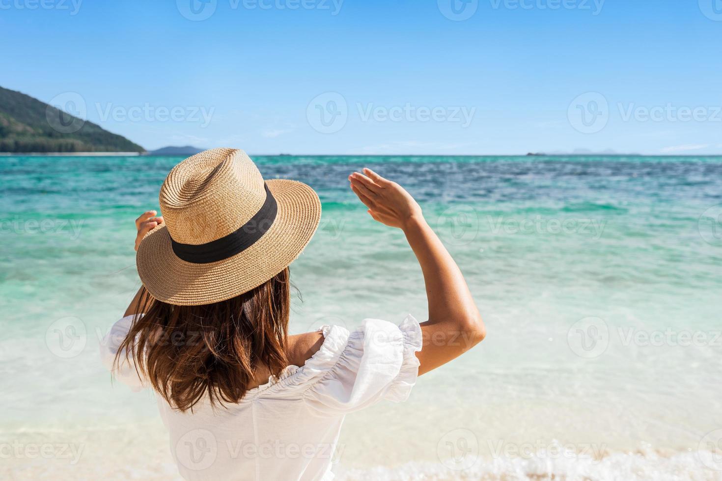 Young woman traveler wearing sunglasses covering face by hand to protect UV rays from the sun at tropical sandy beach on sunny day, Skin care and eyes protect concept photo