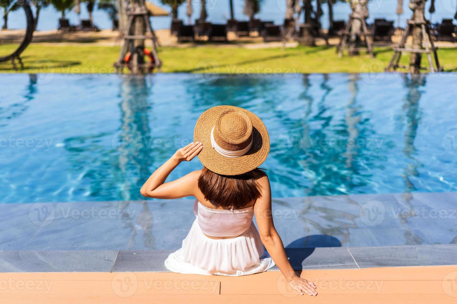 Young woman traveler relaxing and enjoying by a tropical resort pool while traveling for summer vacation photo