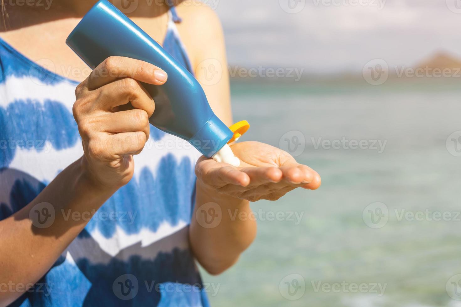 Young woman traveler applying sunscreen lotion the tropical beach, Summer vacation concept photo