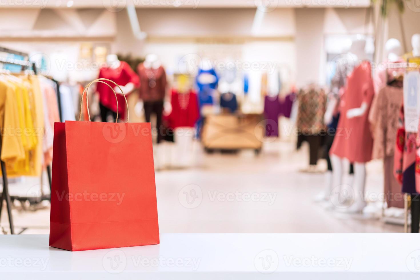 Red paper shopping bags with abstract blurred background of interior clothing store at Shopping Mall photo