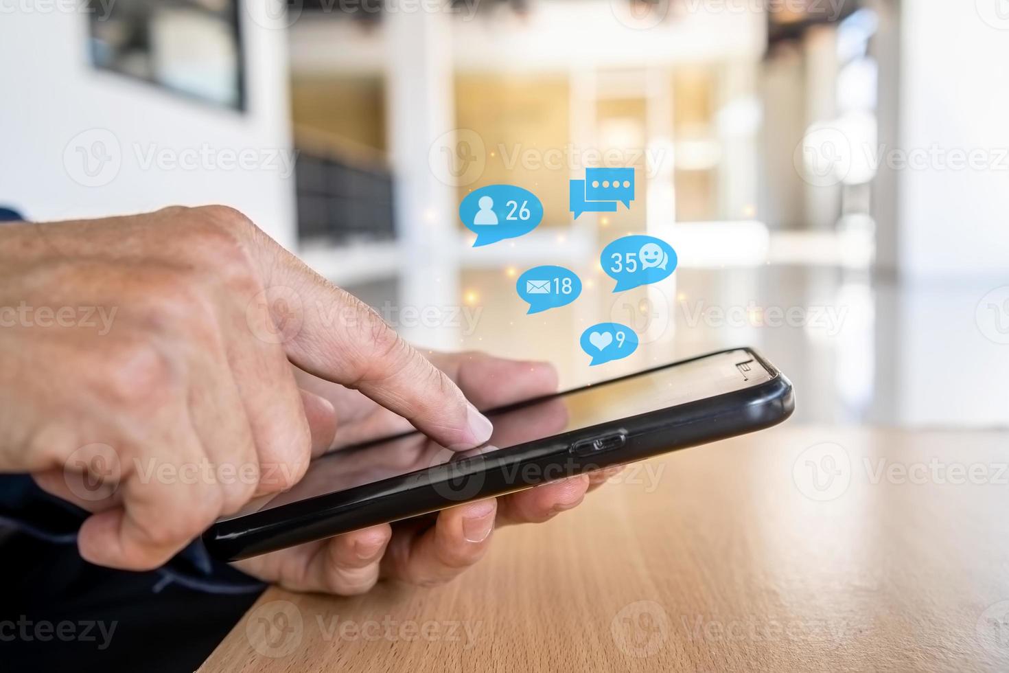 Close-up view of the cell phone in the hands of a man, person using a social media marketing concept on mobile phone with notification icons of like, message, comment and star above smartphone screen photo