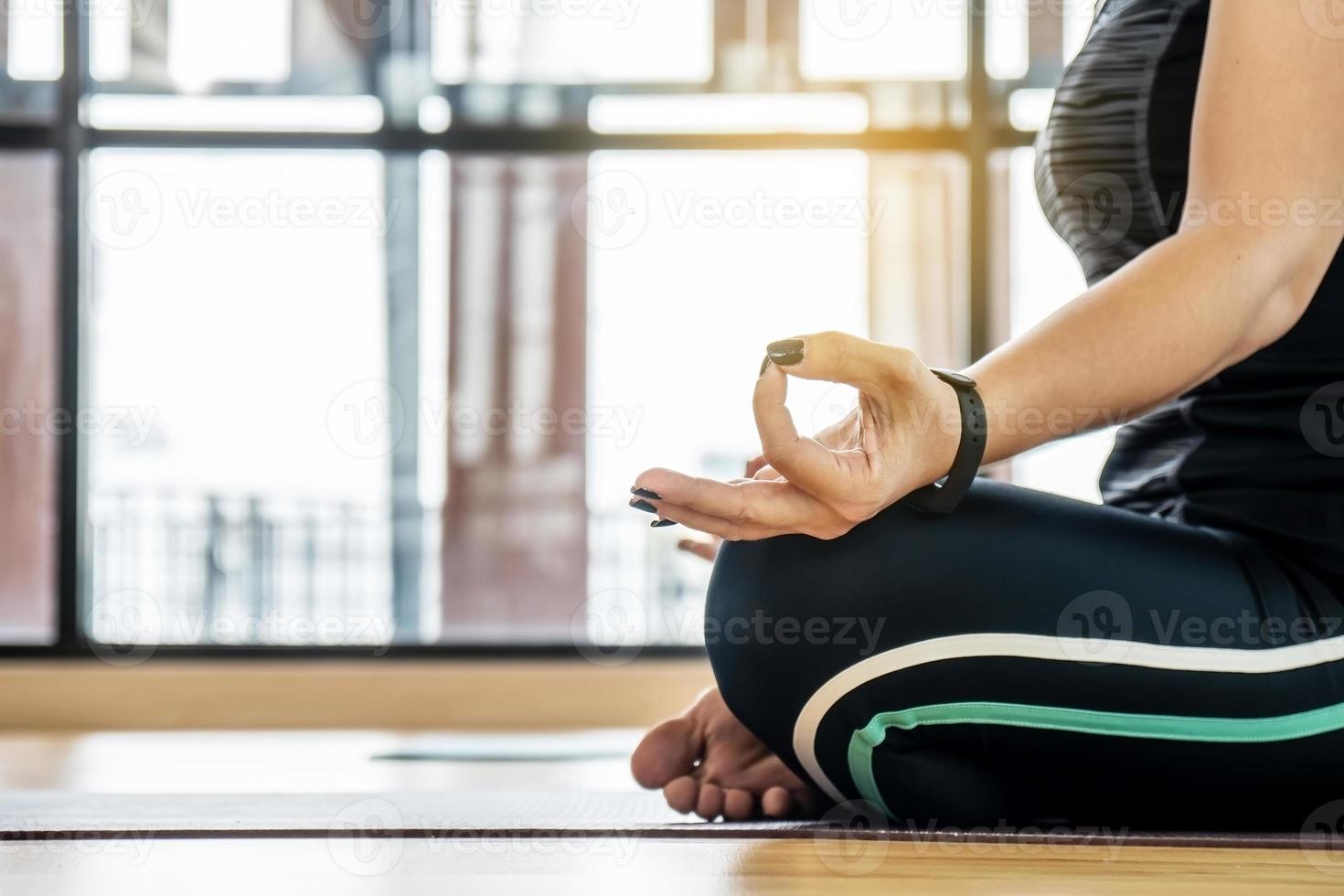 Attractive young woman exercising and sitting in yoga Lotus pose with mudra gesture position while resting at home, Concept of healthy life and natural balance between body and mental development photo