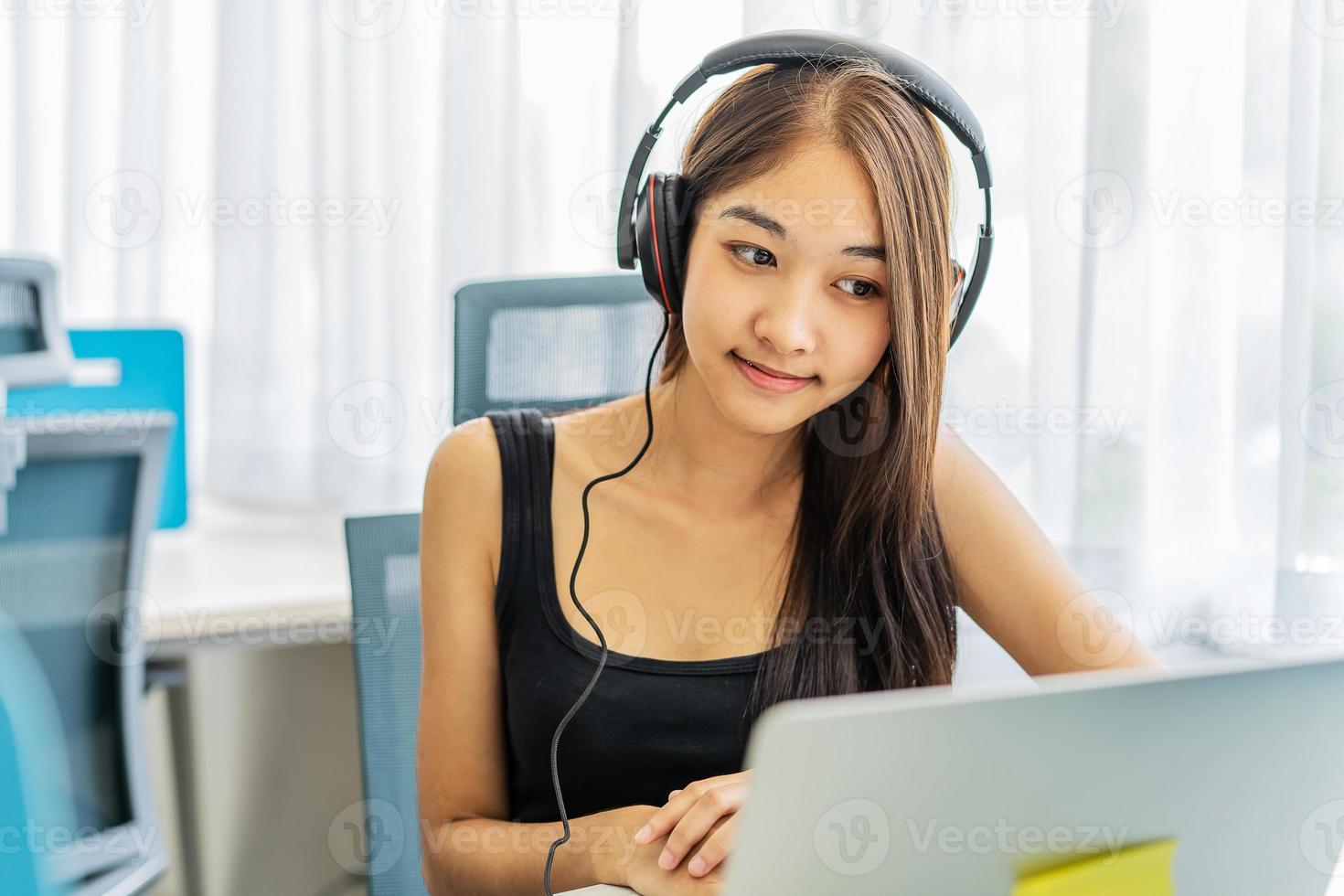 Happy asian girl sitting at desk looking at camera prepare for exams, young woman wear headphones studying via internet doing online tasks e-learning. Self education and knowledge concept photo
