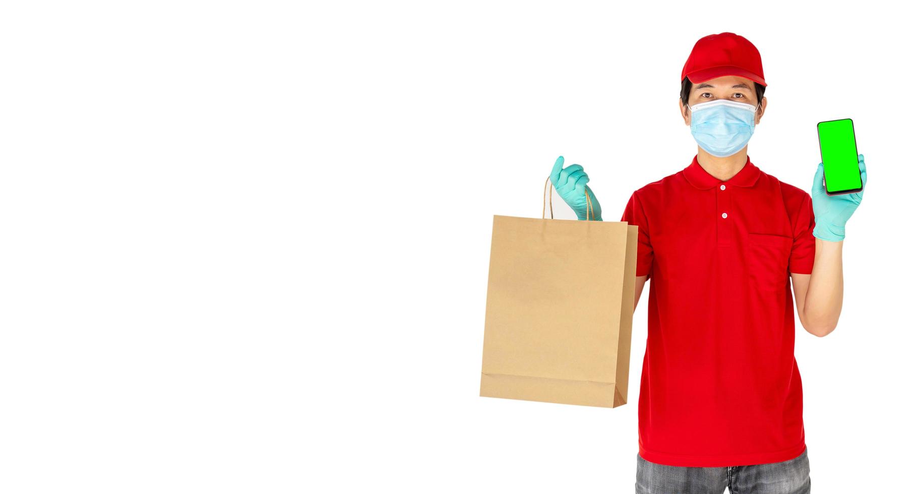 Delivery man employee in red cap t-shirt uniform mask gloves hold craft paper packet with food and phone isolated on white background, Service quarantine pandemic coronavirus virus flu concept photo