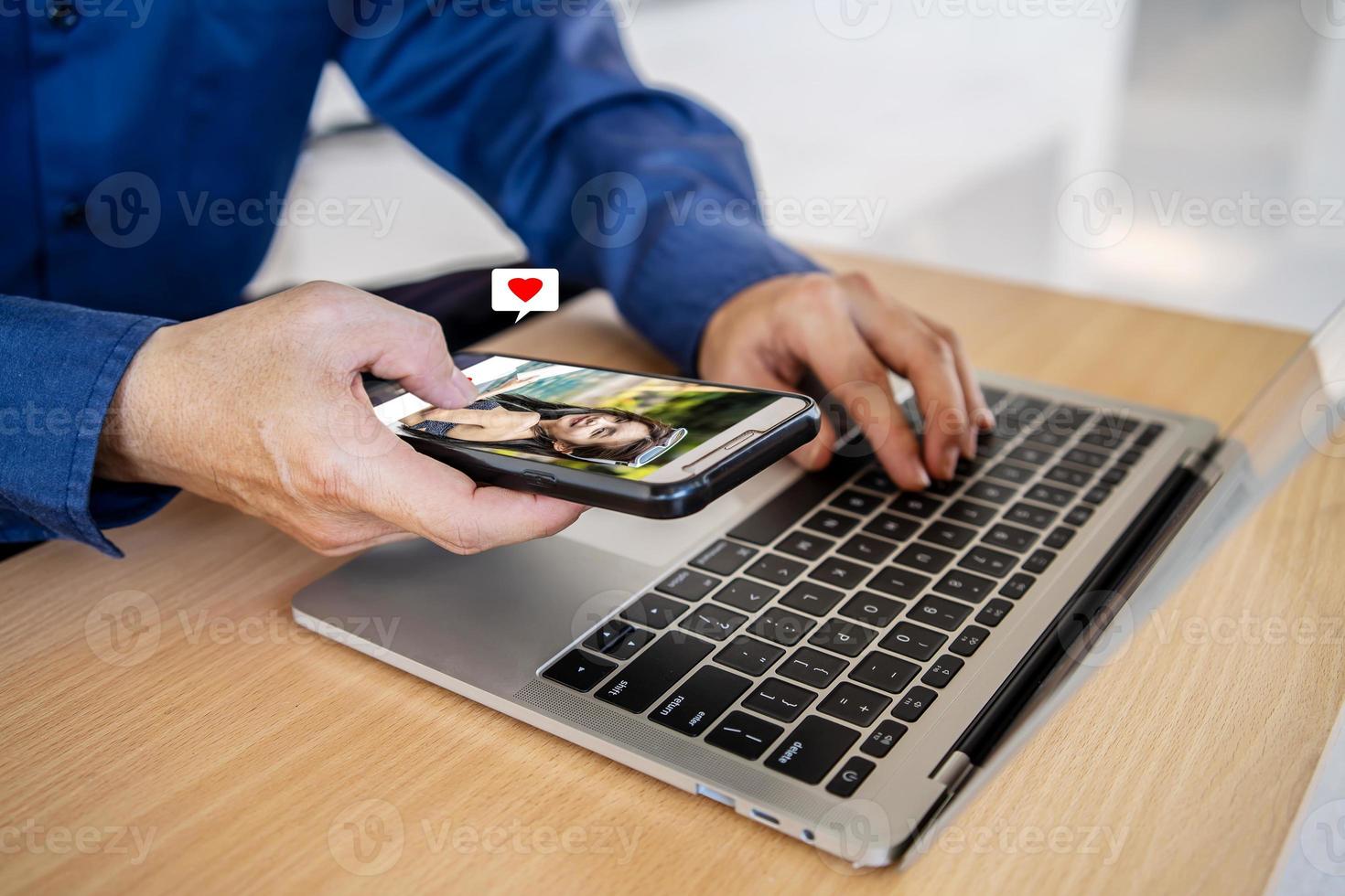 Finding love online using dating websites or mobile apps, Man holding mobile phone, looking at attractive young woman's profile photo on dating app and pressing red heart like button.