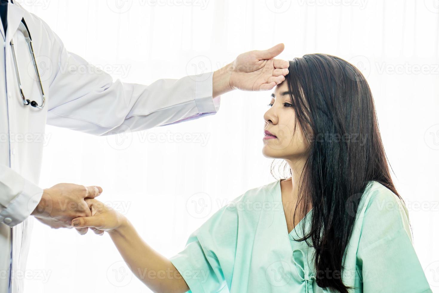 Male doctor uses the back of her hand to touch the forehead of a female patient, checking her sick patient's temperature. The concept of health examination. photo