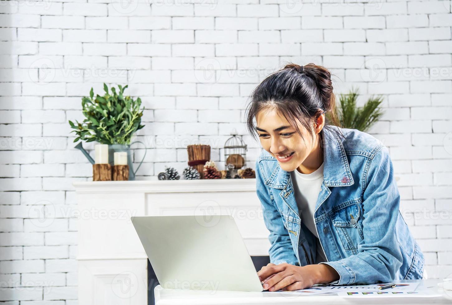 Young smiling happy asian woman relaxing connected on internet with laptop computer working and video conference meeting at home.Young creative typing on keyboard, work from home concept photo