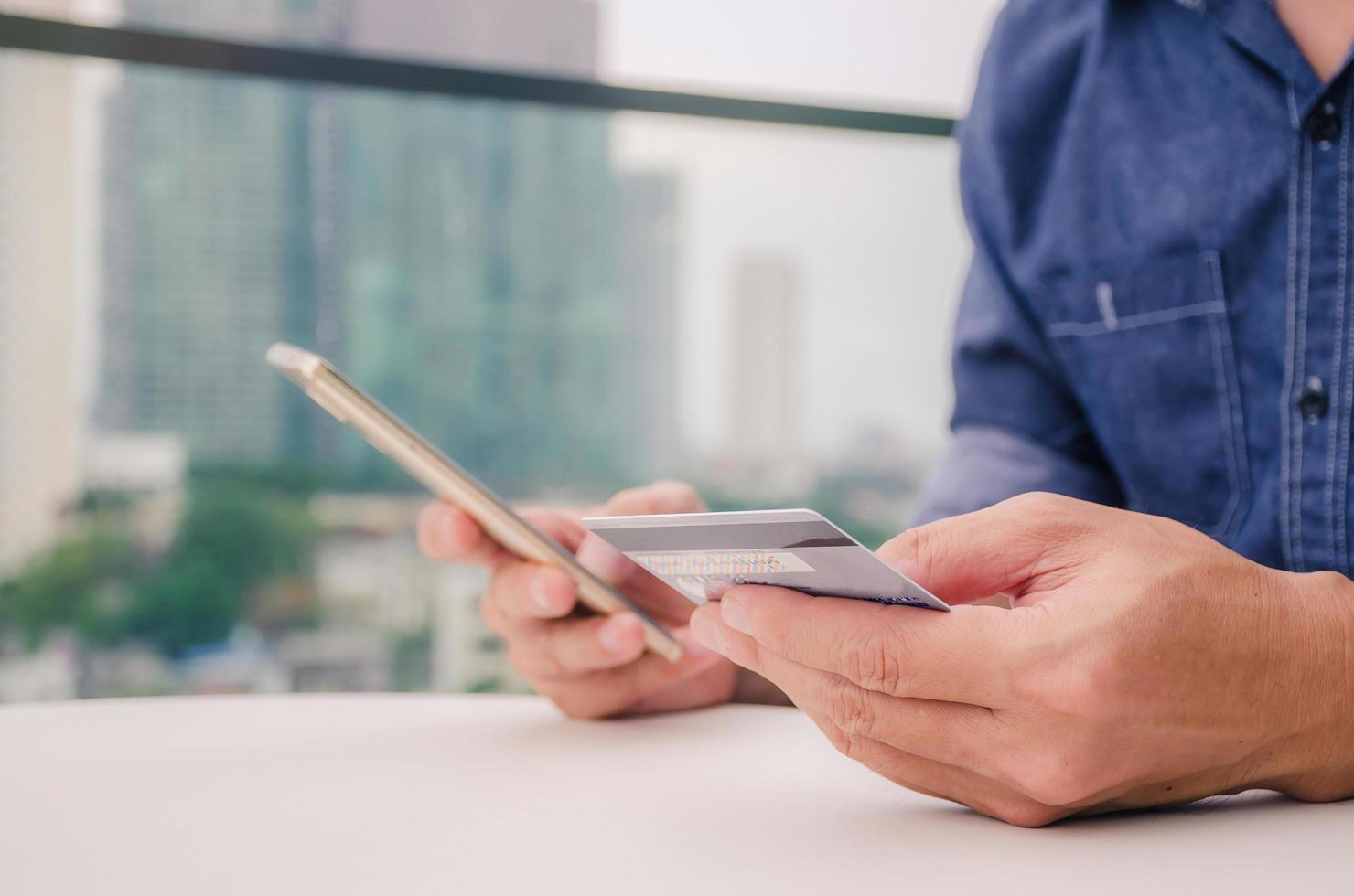 Online payment, Closeup young man hands holding a credit card and using smart phone for online shopping or reporting lost card is city outside background, New generation gadget photo